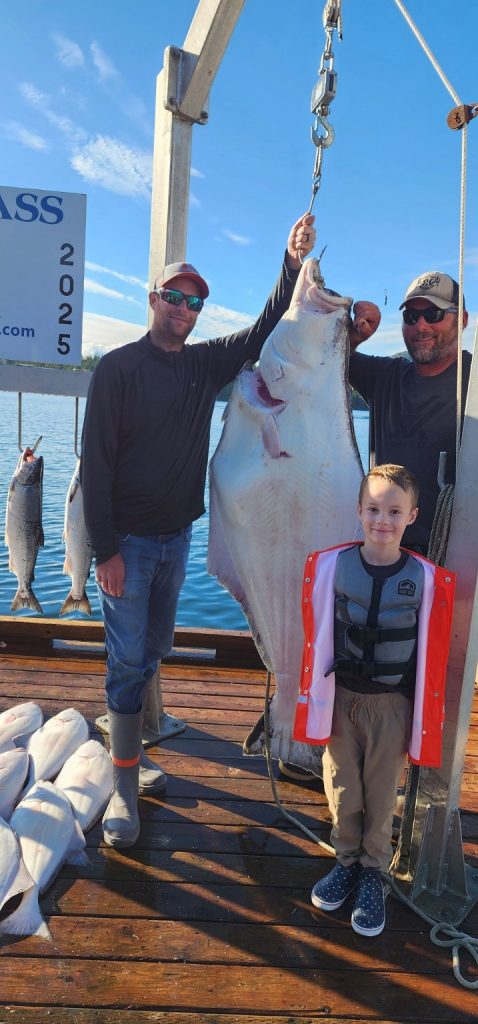 Adults and a child with a huge halibut at the dock