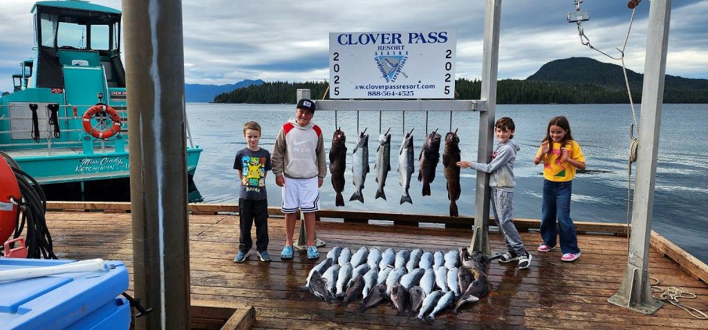 Four smiling kids with the day’s salmon and rockfish at the Clover Pass dock