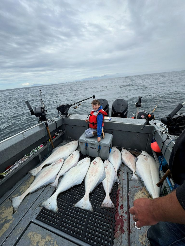 Young angler with the day's salmon and halibut on the boat deck