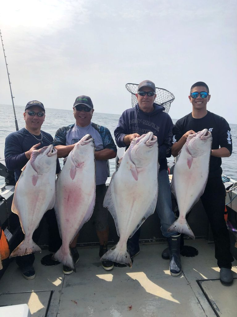 Four guests each holding a halibut caught off Ketchikan