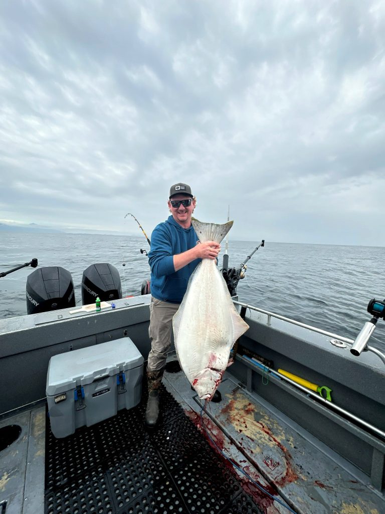 Guest holding a halibut caught bottom fishing out of Ketchikan