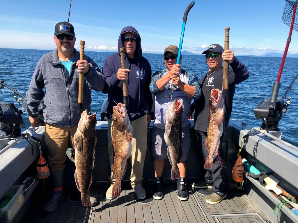 Four guests holding lingcod and rockfish aboard the boat