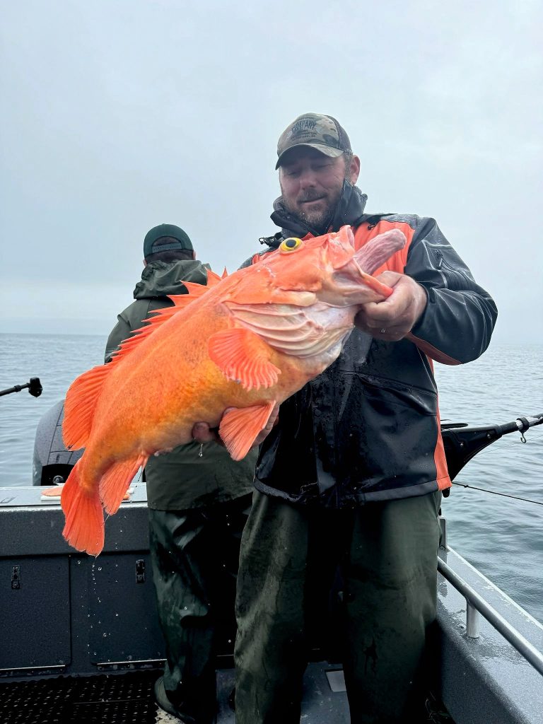 Guest holding a bright orange rockfish caught bottom fishing