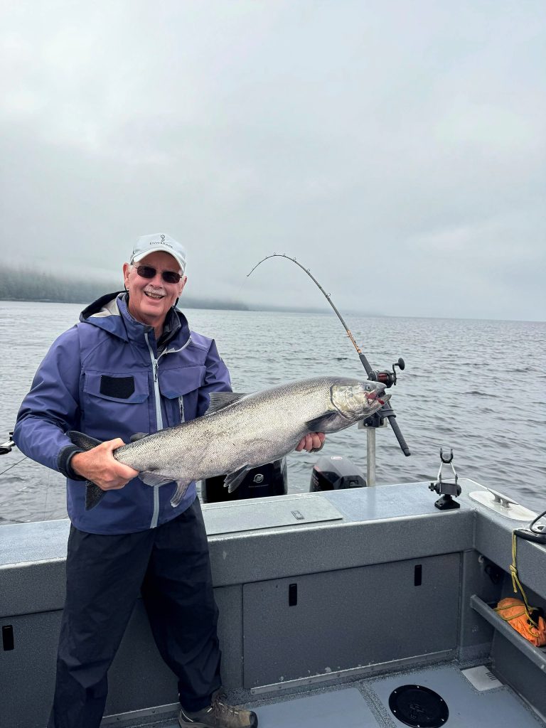 Guest holding a salmon on calm water near Ketchikan