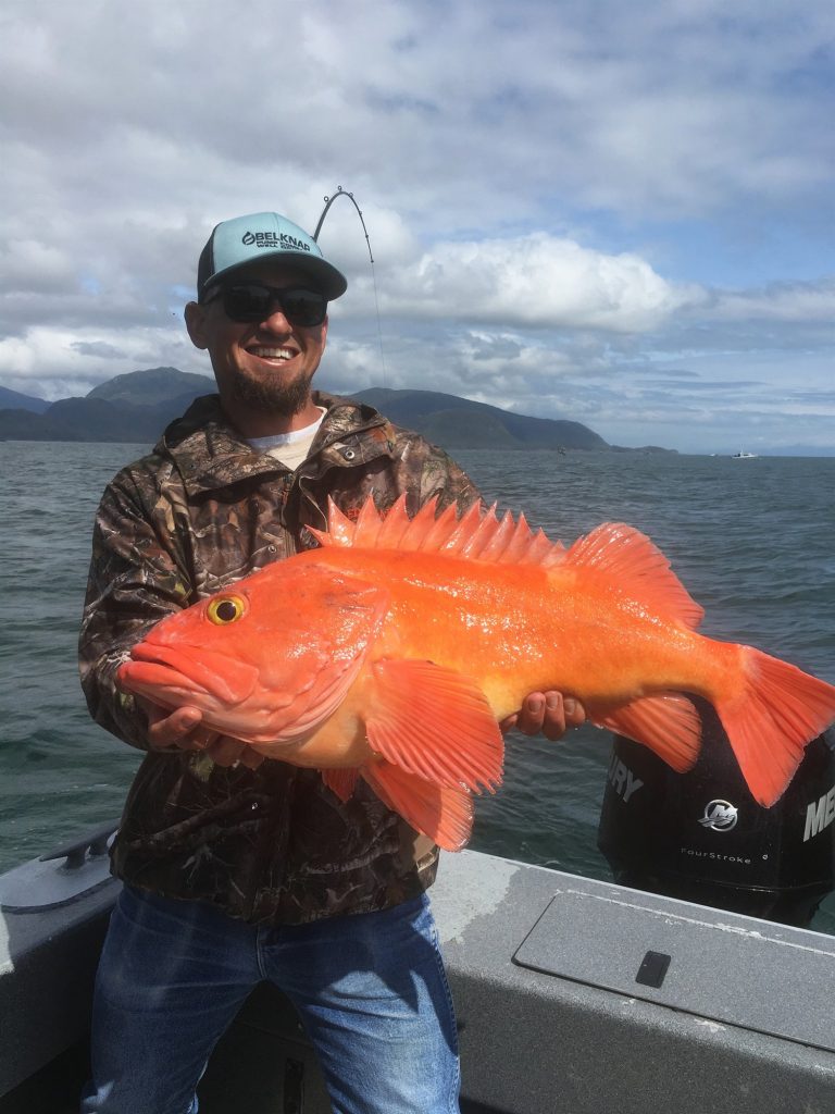 Bright orange rockfish held up on the boat