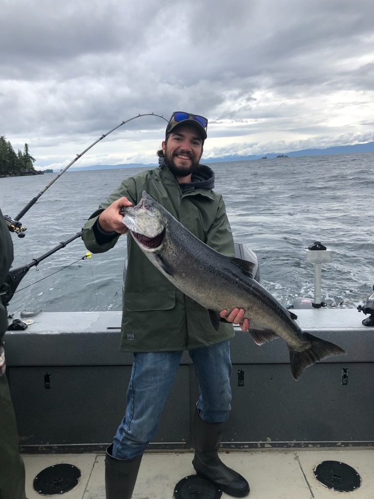 Angler on the boat holding a salmon caught trolling