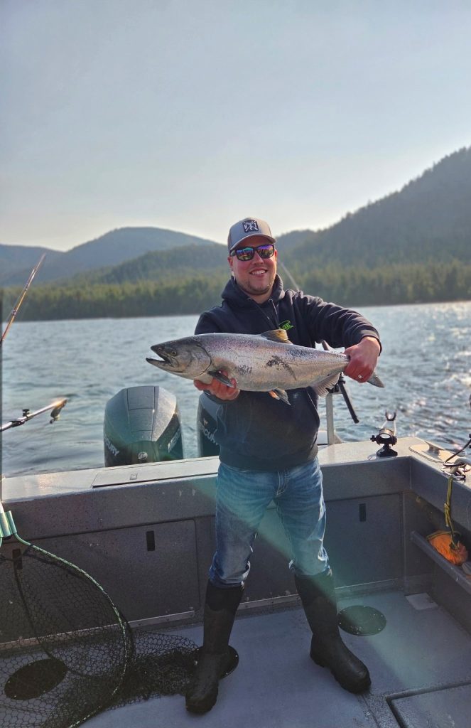 Angler with a salmon against mountains and water