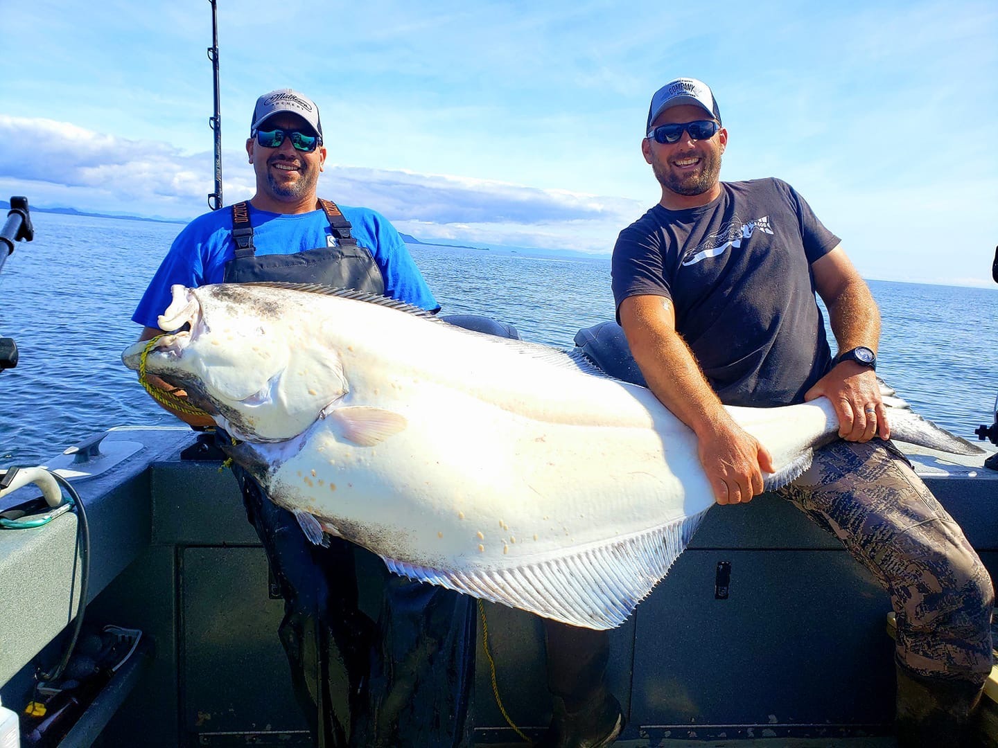 Captain Jim and a guest holding a very large halibut on the boat
